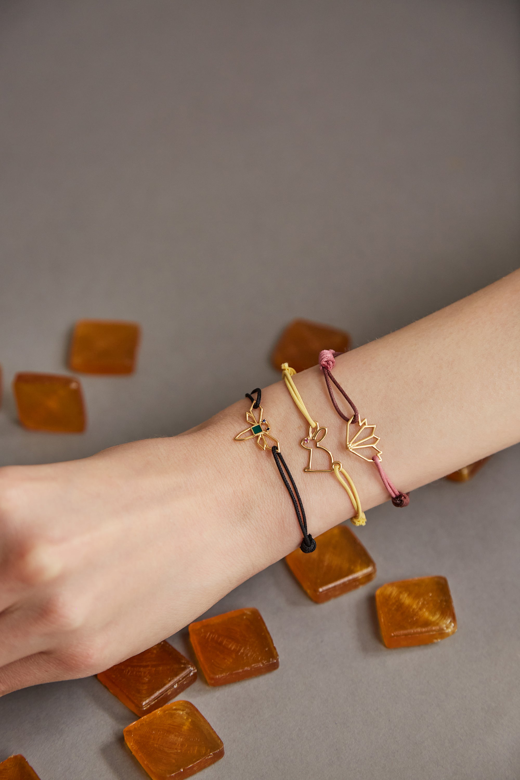 Woman wearing cord bracelets with gold pendants with precious stones