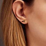 Gold earrings pair with baguette cut garnet and green tourmaline on woman