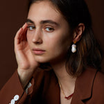 Model wearing gold earring with fresh water baroque pearl
