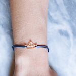 Blue cord bracelet with boat shaped gold pendant on model
