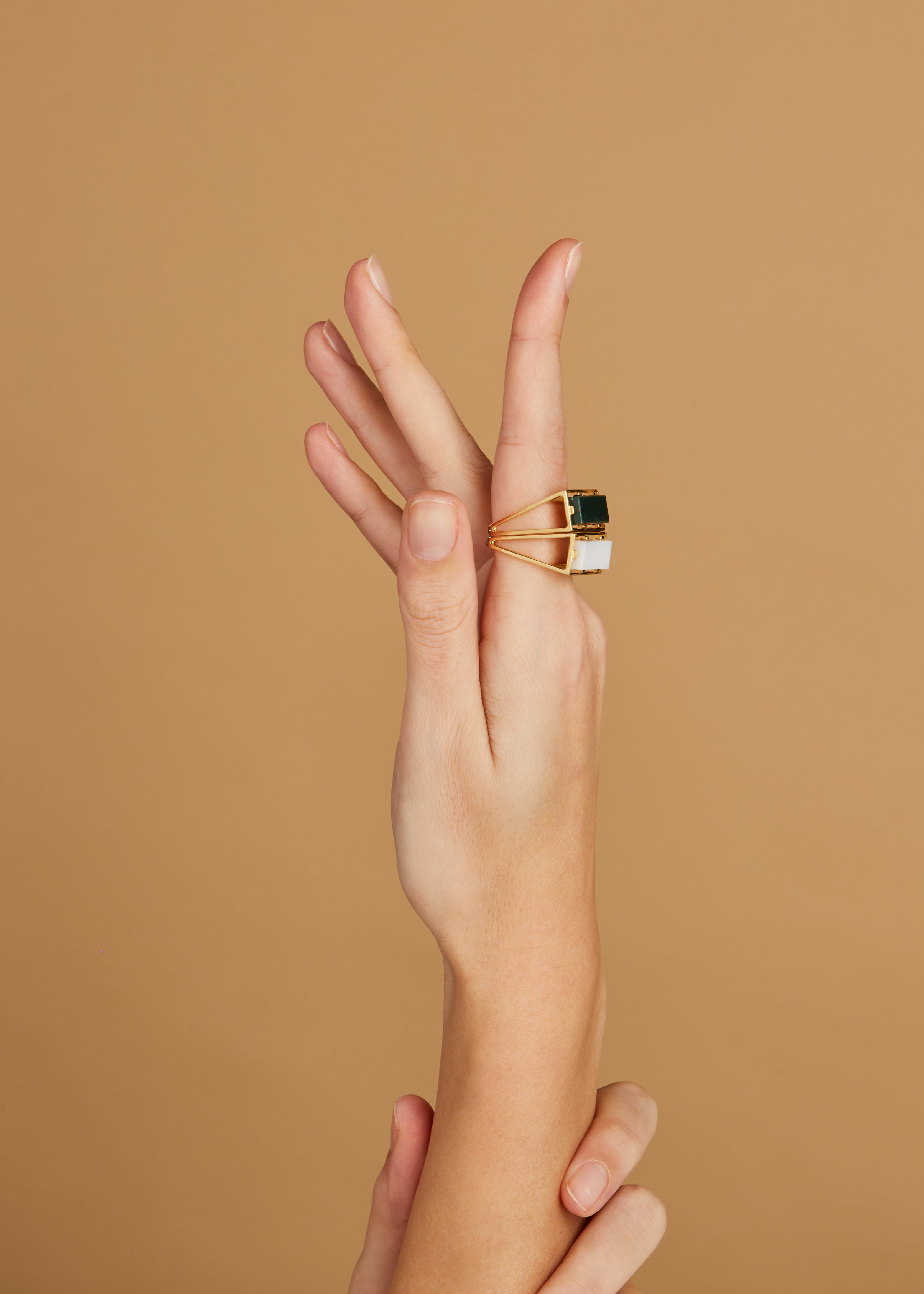 Gold square rings with white agate and jasper stones on woman's hand