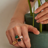 Hands wearing gold rings with cylinder cut malachite stones
