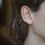 Mini gold hoop earrings worn by model