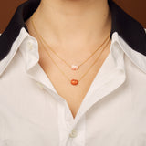Gold chain necklace with mini red crab shaped coral worn by model