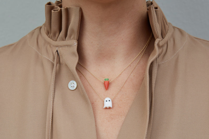 Model wearing gold chain necklaces with carrot shaped coral pendants and ghost shaped white coral pendant