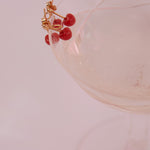 Champagne glass with coral cherries gold earrings on top