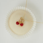 Creamy white pastry with a necklace with coral cherries as pendant on top