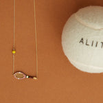 Gold chain necklace with gold tennis racquet and ball shaped pendants in pink and yellow enamel detail