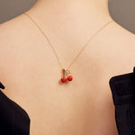 Woman shot from the back wearing a gold chain necklace with two cherries in red coral