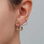 Seated cat shaped earring and heart shaped earring worn by woman