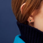 Woman wearing a dragonfly shaped gold earring with blue sapphire and green enamel
