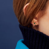 Woman wearing a dragonfly shaped gold earring with blue sapphire and green enamel