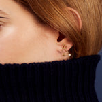 Woman wearing a small rabbit shaped gold earring with a pearl tail