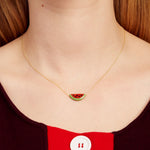 Woman wearing a gold chain necklace with a watermelon slice in red coral and oxidized turquoise
