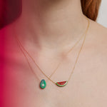 Woman wearing a gold chain necklace with a watermelon slice in red coral and a necklaces with avocado in green turquoise