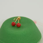 Green sweet pastry with coral cherries gold earring on top