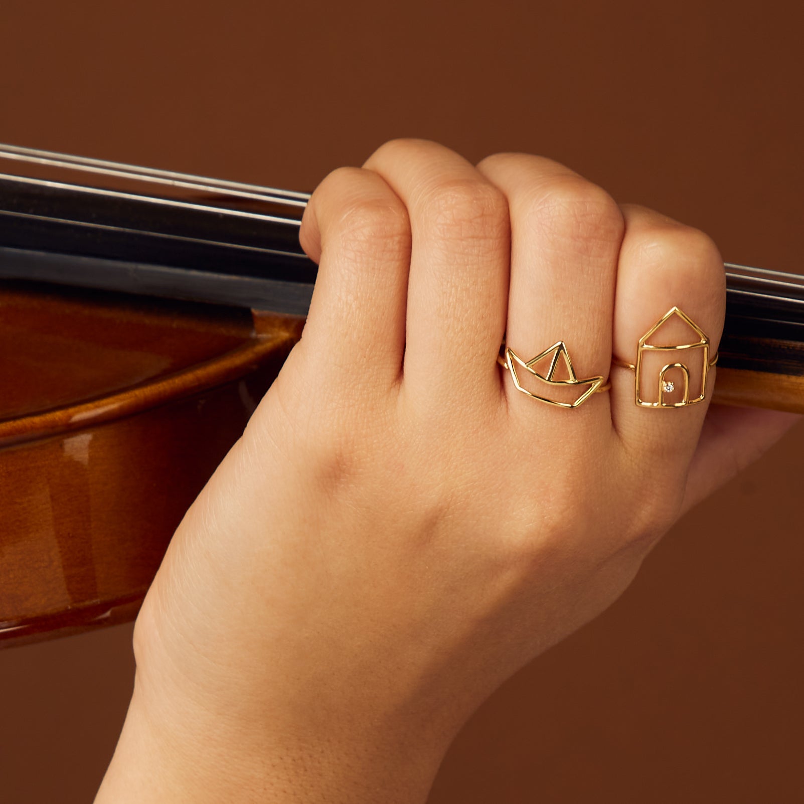 House and little boat shaped gold rings on woman's hand