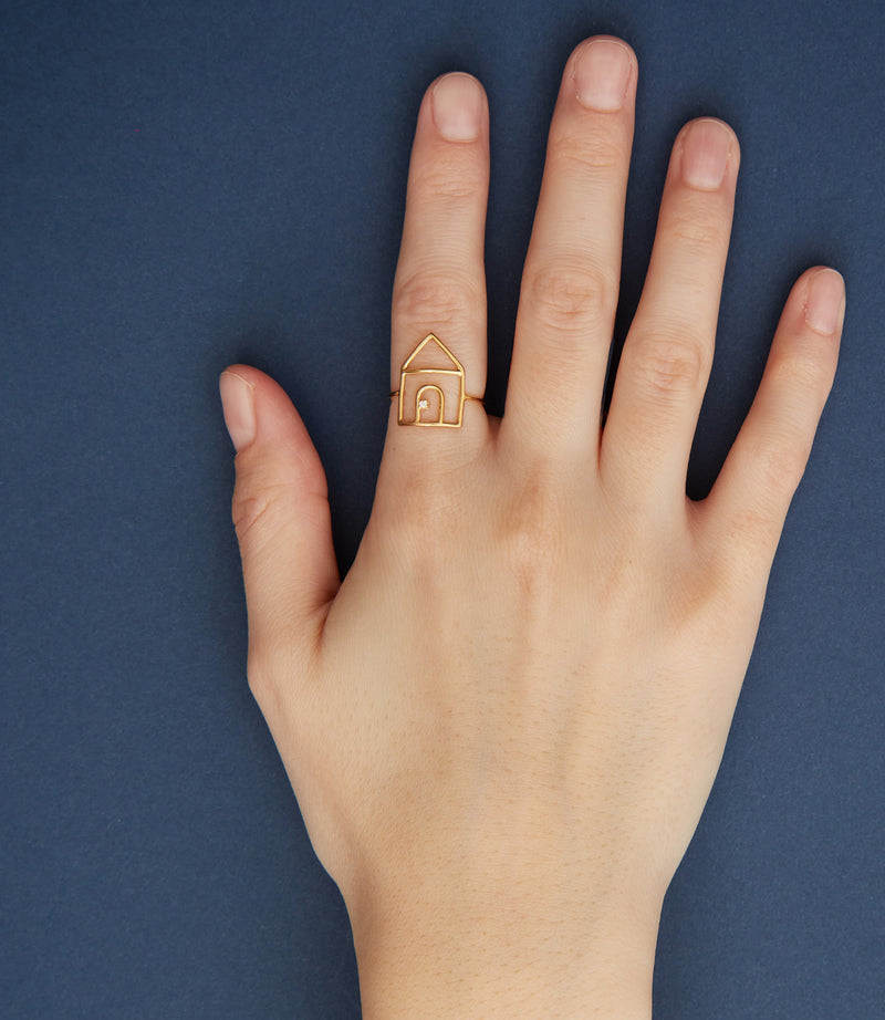 House shaped gold ring with small diamond on woman's hand