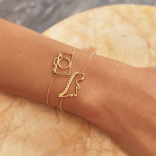 Carica l&#39;immagine nel visualizzatore di Gallery, Gold chain bracelets with dinosaur and camera shaped pendant with small diamond worn by model

