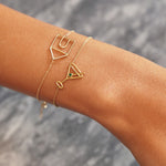Gold chain bracelet with martini drink shaped pendant and small emerald worn by woman