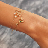 Gold chain bracelet with martini drink shaped pendant and small emerald worn by woman