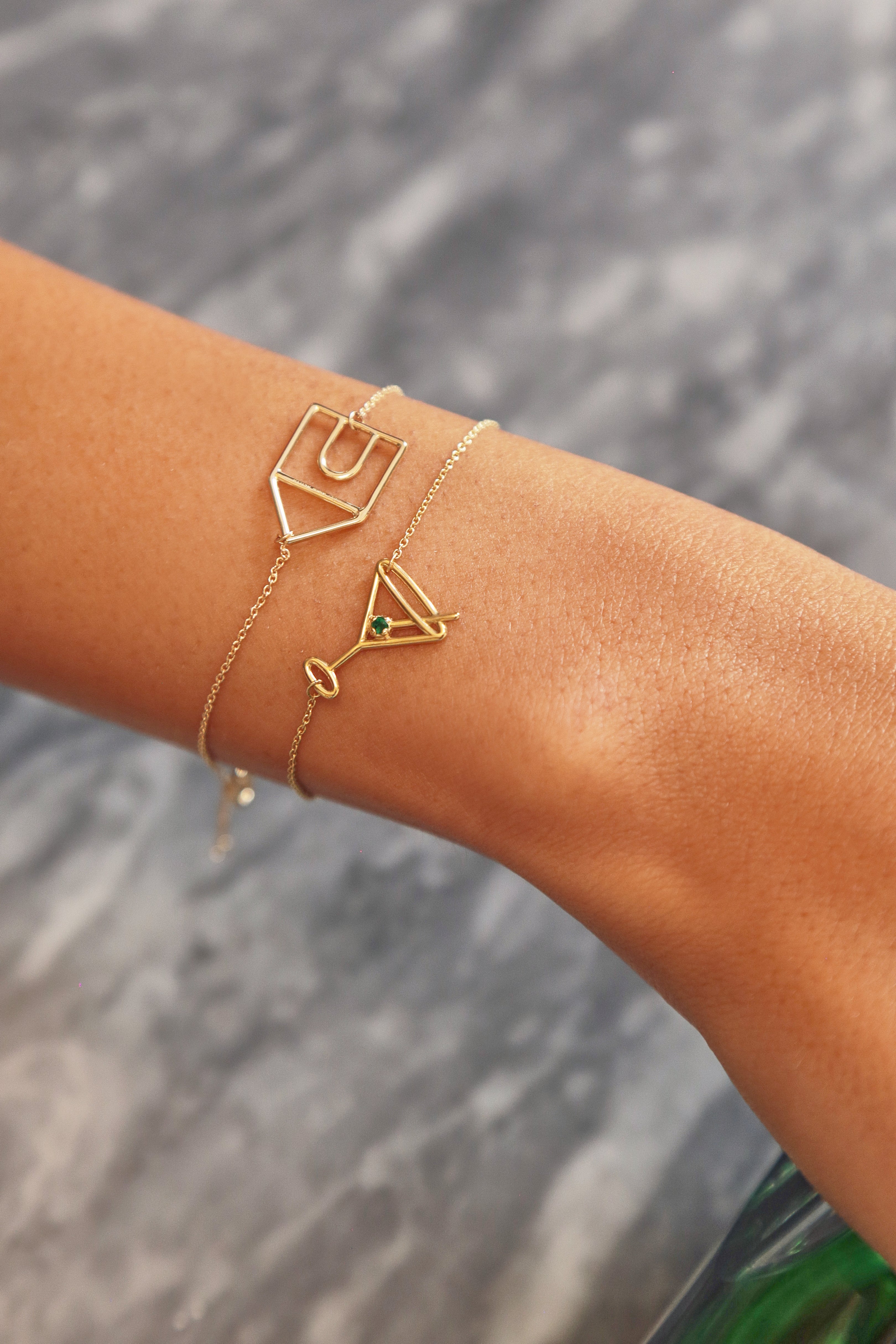 Gold chain bracelet with martini drink shaped pendant and small emerald worn by woman