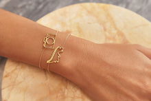 Carica l&#39;immagine nel visualizzatore di Gallery, Gold chain bracelets with dinosaur and camera shaped pendants and small diamond worn by model
