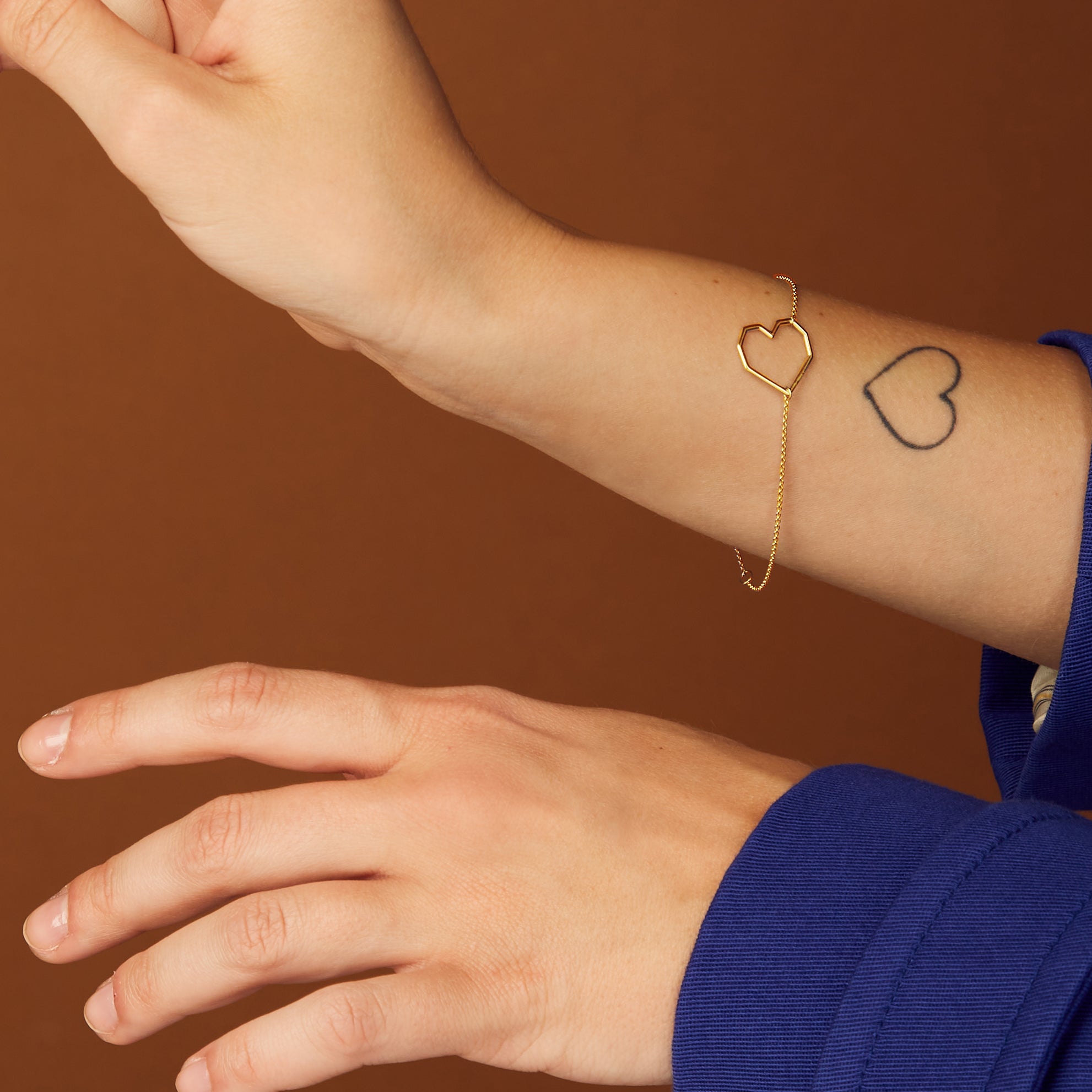 Gold chain bracelet with heart shaped pendant worn by model