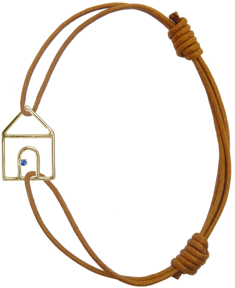Brown cord bracelet with gold house shaped pendant and small blue sapphire