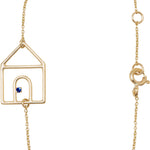 Gold chain bracelet with house shaped pendant and small blue sapphire