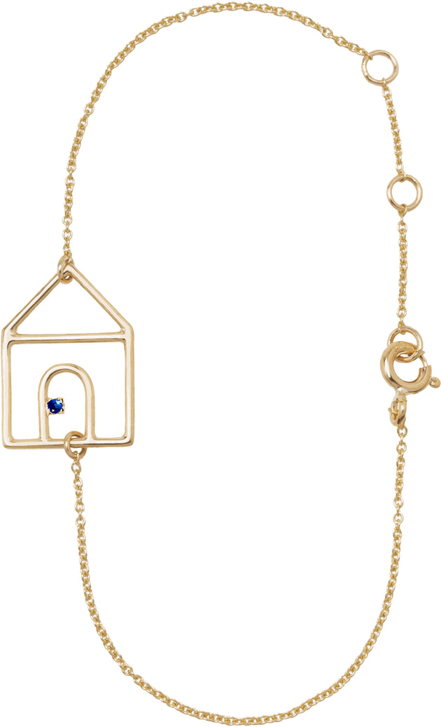 Gold chain bracelet with house shaped pendant and small blue sapphire