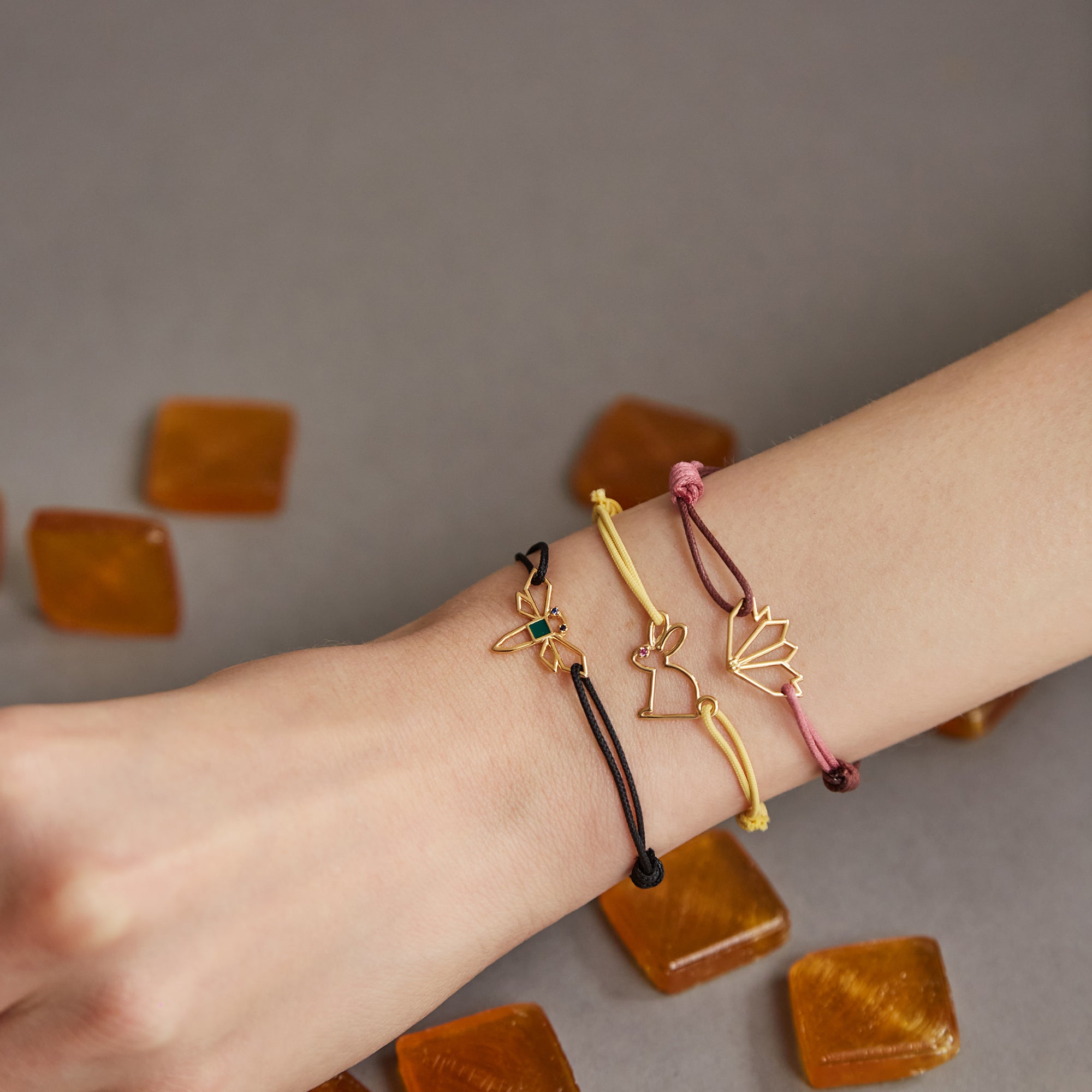 Woman wearing cord bracelets with gold pendants with precious stones