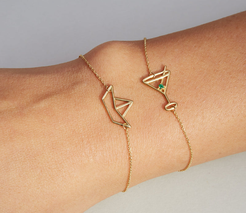 Gold chain bracelets with paper boat and martini drink shaped pendants on model