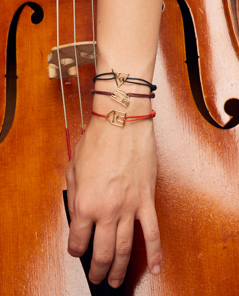 Hand playing cello wearing cord bracelets with gold pendants