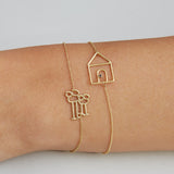 Gold chain bracelets with family and house shaped gold pendants on model's wrist