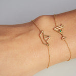 Gold chain bracelet with martini drink shaped pendant and small emerald worn by model