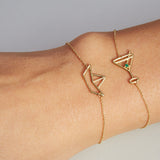 Gold chain bracelet with martini drink shaped pendant and small emerald worn by model