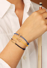 Load image into Gallery viewer, Blue cord bracelet with gold drum shaped pendant worn by model
