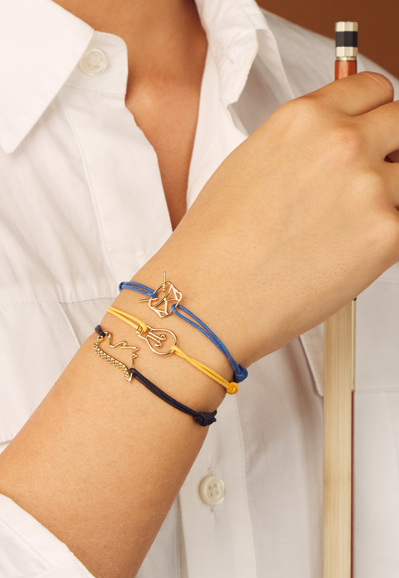 Blue cord bracelet with gold drum shaped pendant worn by model