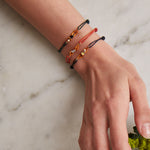 Bottle green cord bracelet with gold swimmer shaped pendant with enamel