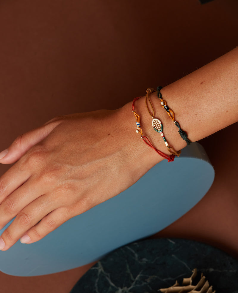 Bottle green cord bracelet with gold swimmer shaped pendant with enamel on model