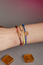 Load image into Gallery viewer, Woman wrist wearing three colorful cord bracelets with gold pendants shaped like a crocodile a turtle and a striped heart
