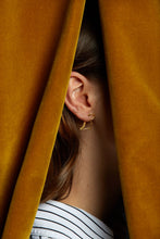Load image into Gallery viewer, Gold dinosaur shaped earring worn by model under curtains

