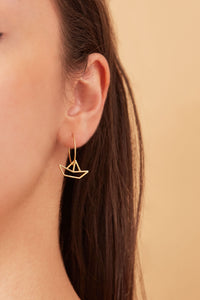 Gold hoop earring with little boat shaped pendant worn by model