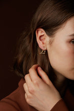 Load image into Gallery viewer, Gold dinosaur shaped earring worn by model
