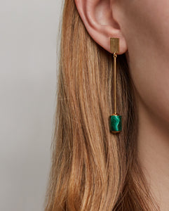 Woman wearing gold long earrings with cylinder cut malachite stone