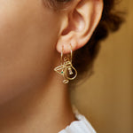 Gold hoop earring with martini drink shaped pendant and small emerald worn by model