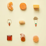 Jewelry and food composition with coral carrot earring and gold necklace
