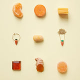 Jewelry and food composition with coral carrot earring and gold necklace
