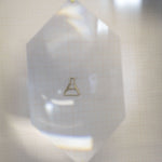 Gold chain necklace with chemistry baker shaped pendant under lens